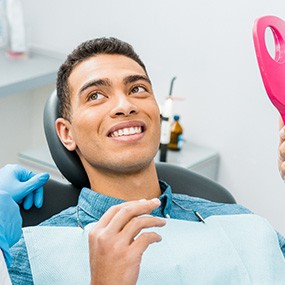 Patient smiling at dentist with pink mirror