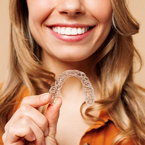 Patient smiling while holding clear aligner