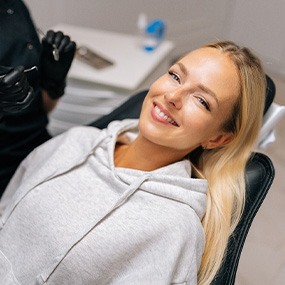 Woman in gray sweatshirt smiling in treatment chair