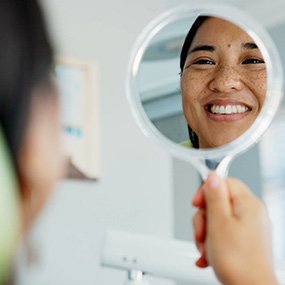 Woman smiling at reflection in dentist office