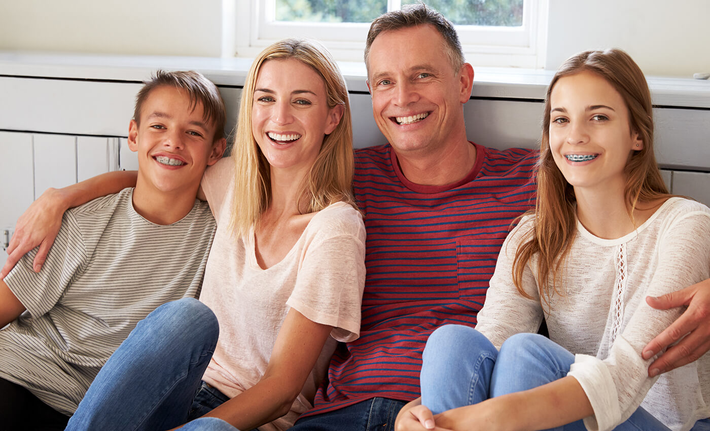 Family of four and two with braces smiling