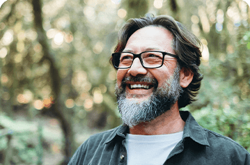Older man with glasses smiling outdoors