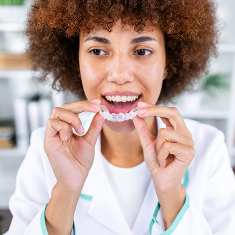 Woman placing an Invisalign clear aligner over her teeth