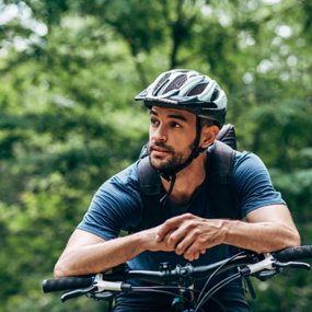 Man with helmet riding bike outside