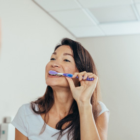 Woman brushing her teeth in bathroom
