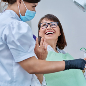 Woman smiling with dentist while reviewing X-ray
