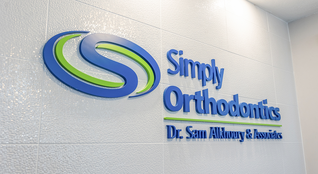 Sign on a wall reading Simply Orthodontics Doctor Sam Alkhoury and Associates
