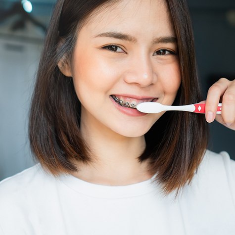 a woman with braces brushing her teeth