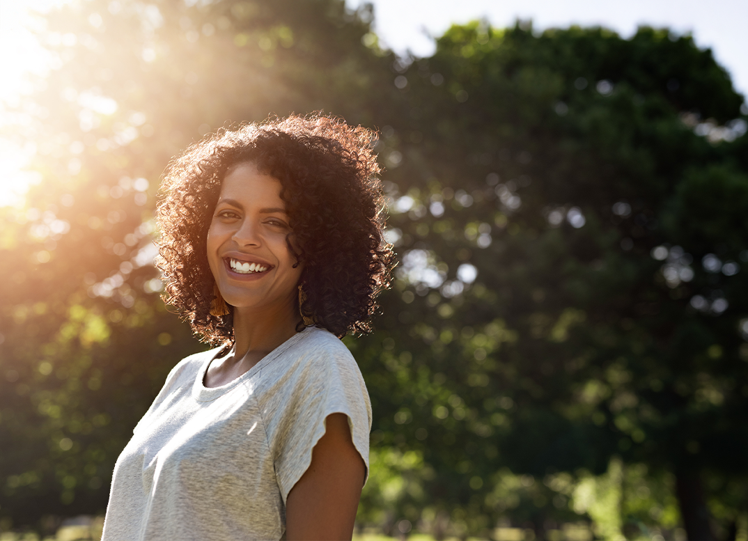 Woman smiling outdoors after seeing an orthodontist in Dayville