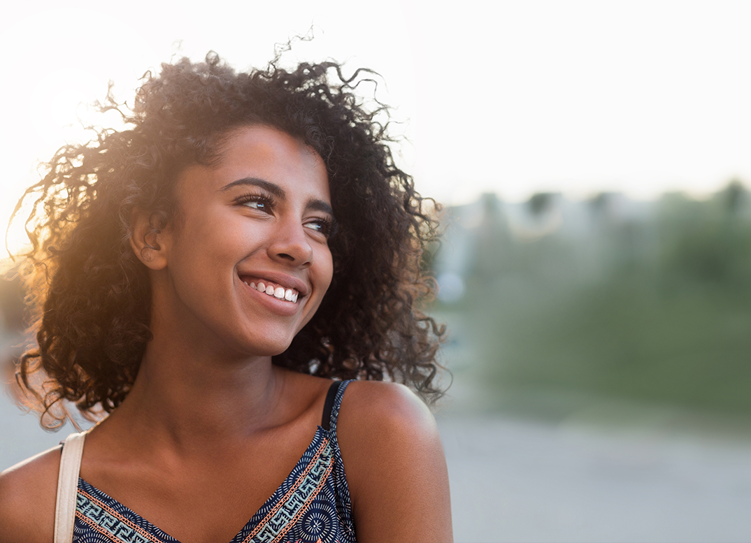 Young woman smiling in the sun after seeing an orthodontist in Derry