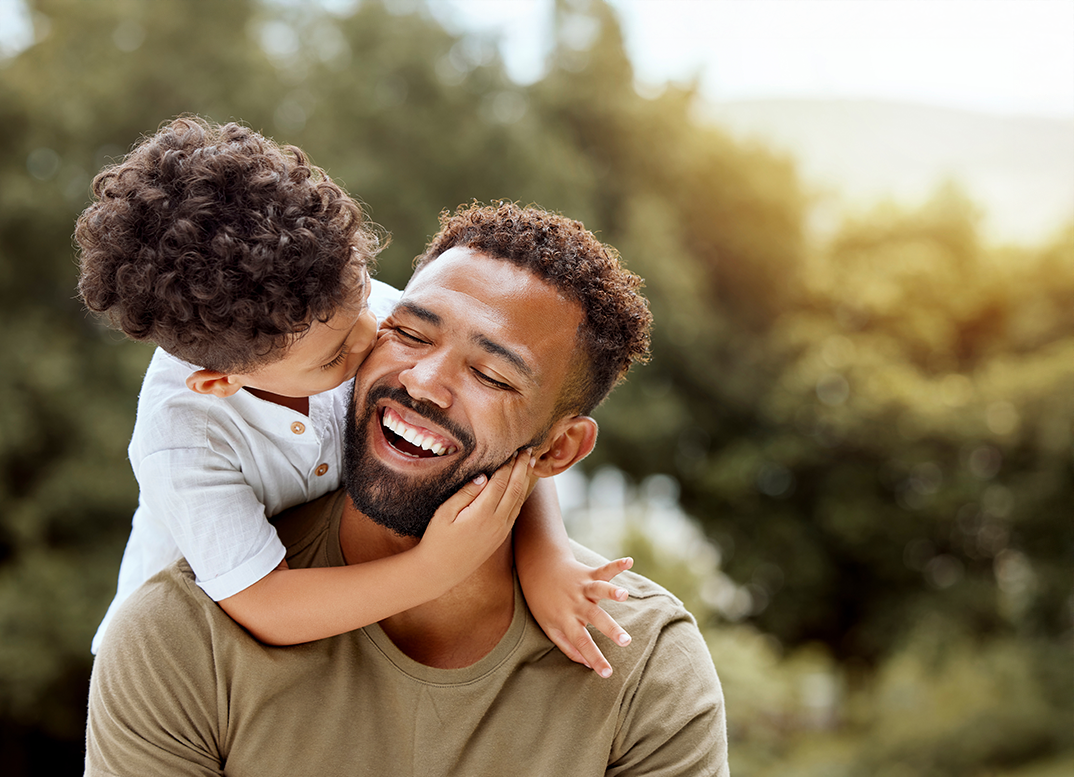 Young boy kissing his father's cheek after seeing an orthodontist in Framingham