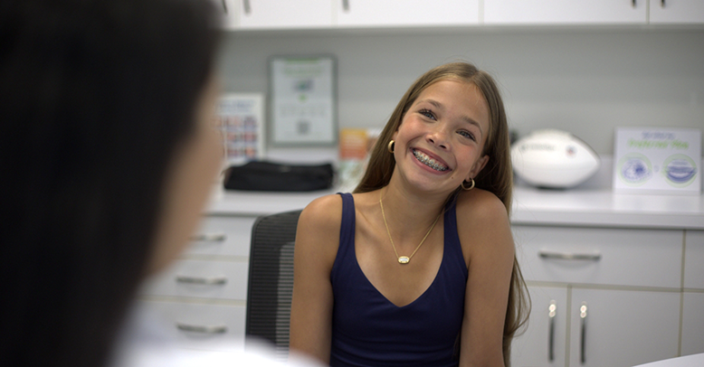 Teenage girl with braces smiling at her orthodontist