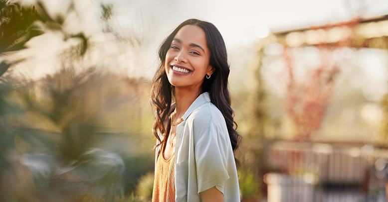 Woman with long dark hair smiling in the sun