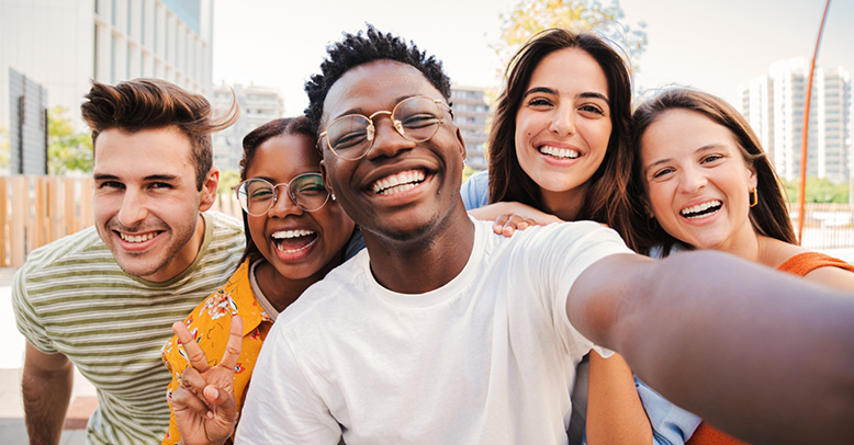 Selfie of five smiling young adults with a city skyline in the background