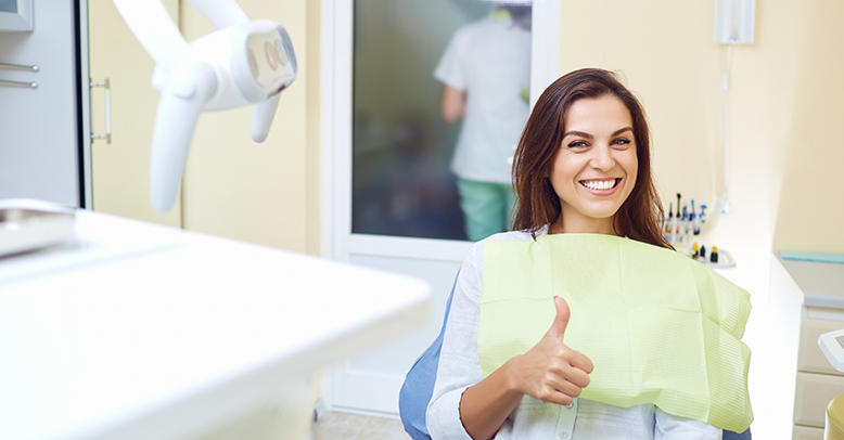 Smiling woman giving a thumbs up in the dental chair