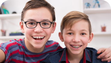 Two smiling boys, one with traditional braces and one without braces