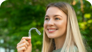 Blonde woman holding an Invisalign clear aligner