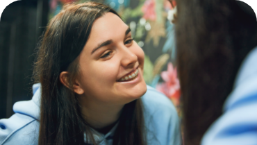 Young woman with ceramic braces smiling in front of a mirror