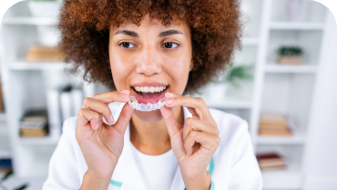 Woman placing a clear aligner over her teeth