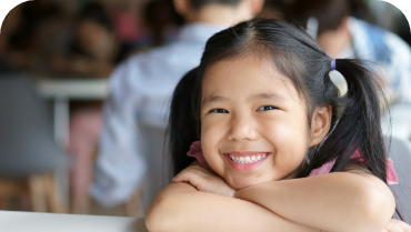Young girl grinning at a desk