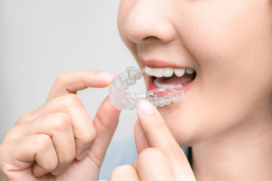 a patient smiling and holding their Invisalign aligner