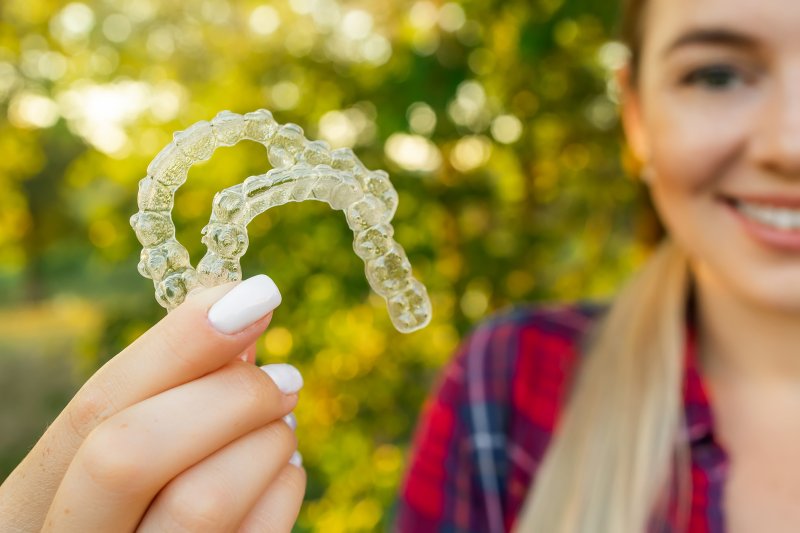 woman holding two clear aligners
