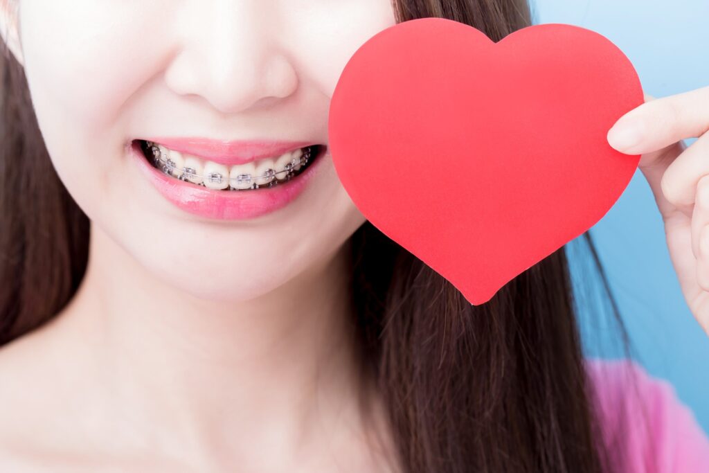 Closeup of smile with braces and paper heart